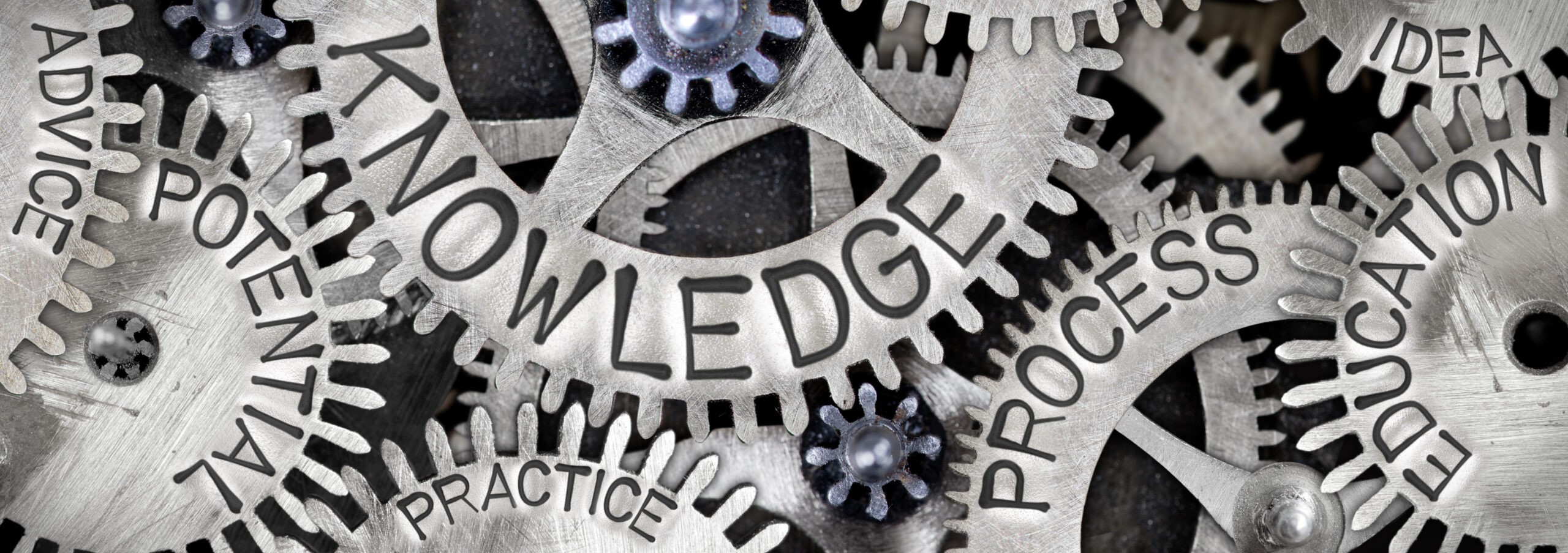 Macro photo of tooth wheel mechanism with KNOWLEDGE concept related words imprinted on metal surface